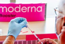 A man pulls up a syringe for a booster vaccination with Moderna Ein Mann zieht eine Spritze für eine Booster-Impfung mit Moderna auf