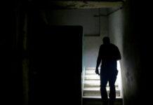 Ein Mann läuft während eines Stromausfalls mit einer Taschenlampe durch ein Treppenhaus.