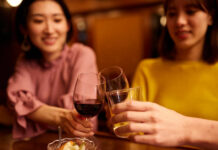 Japanische Freundinnen sitzen in einer Bar und trinken Wein.