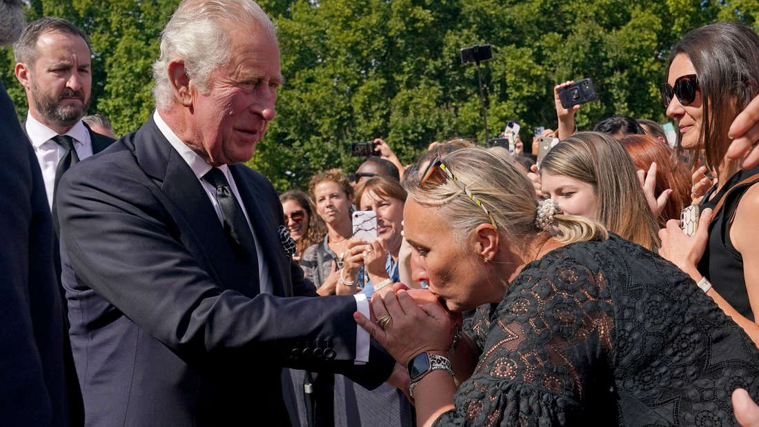 Eine Frau küsst die Hand von König Charles III. bei seinem Rundgang vor dem Buckingham-Palast in London.
