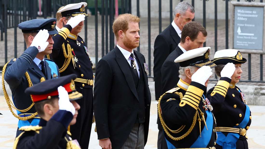 Prinz William (links), Vater König Charles III. und Prinzessin Anne salutieren in Uniform, währen Prinz Harry in zivil seine Ehre erweist.