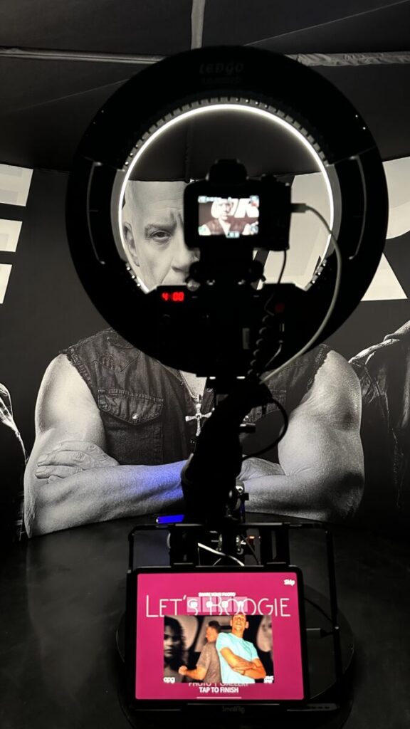 Guests on the 360 photo booth platform in front of a Vin Diesel backdrop at a Fast X event