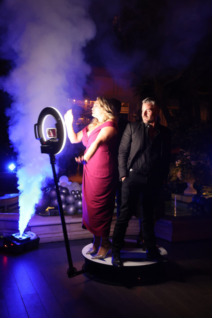 Two guests on the 360 photo booth platform surrounded by fog under a ring light