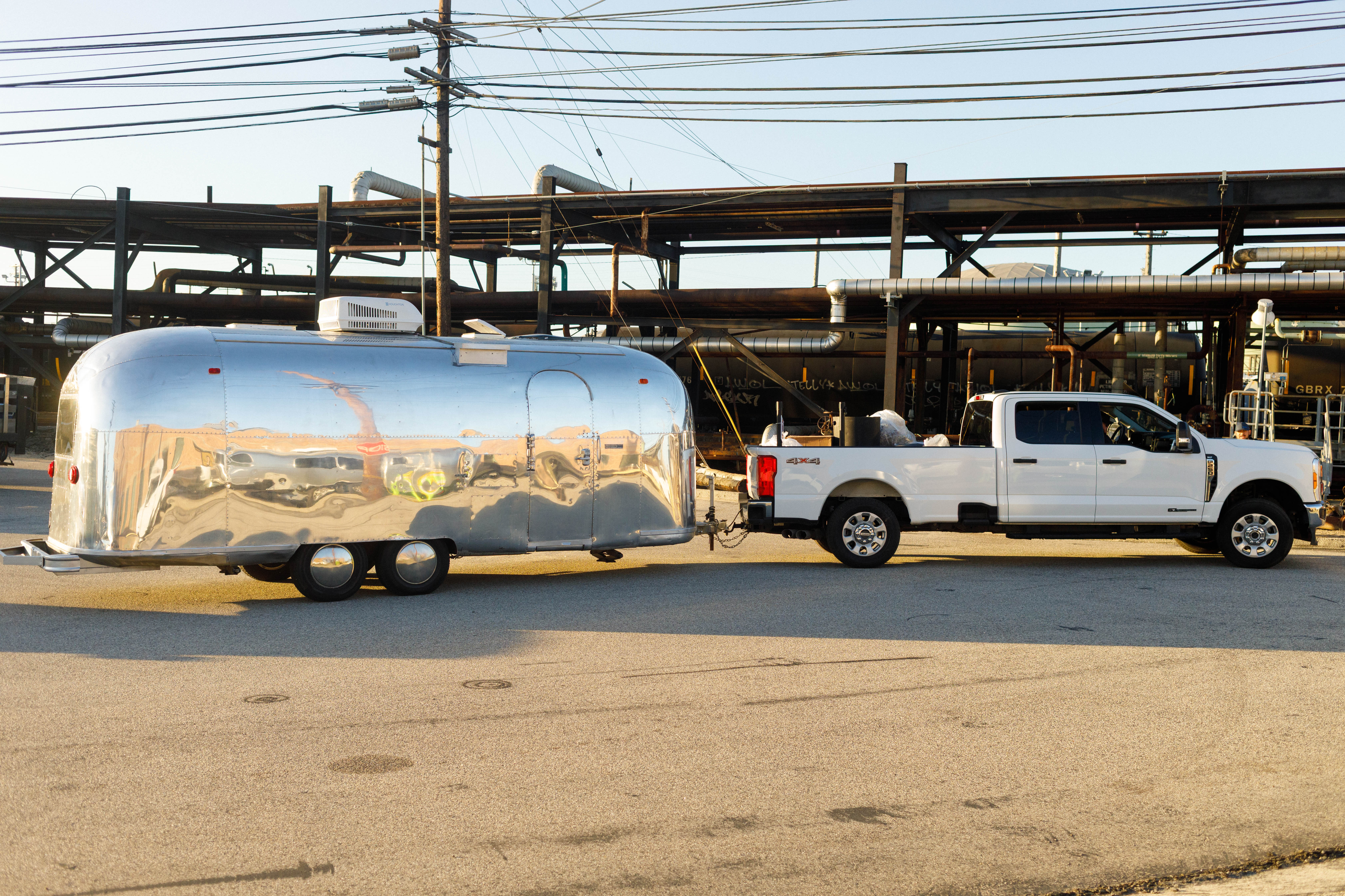 Airstream trailer being towed into the Chevron El Segundo Refinery by a white pickup truck