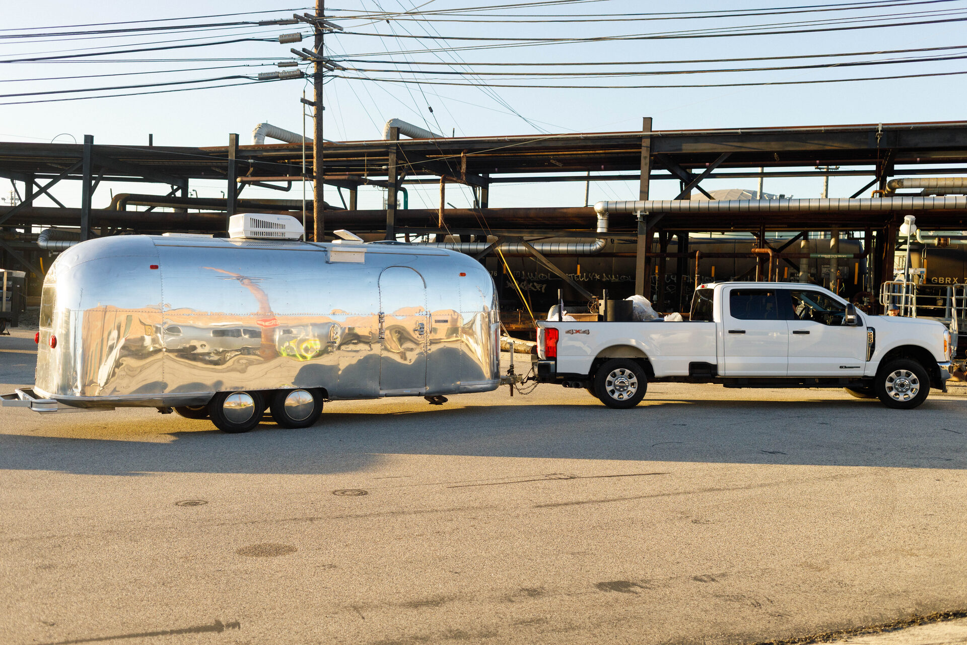 Airstream trailer being towed into the Chevron El Segundo Refinery by a white pickup truck