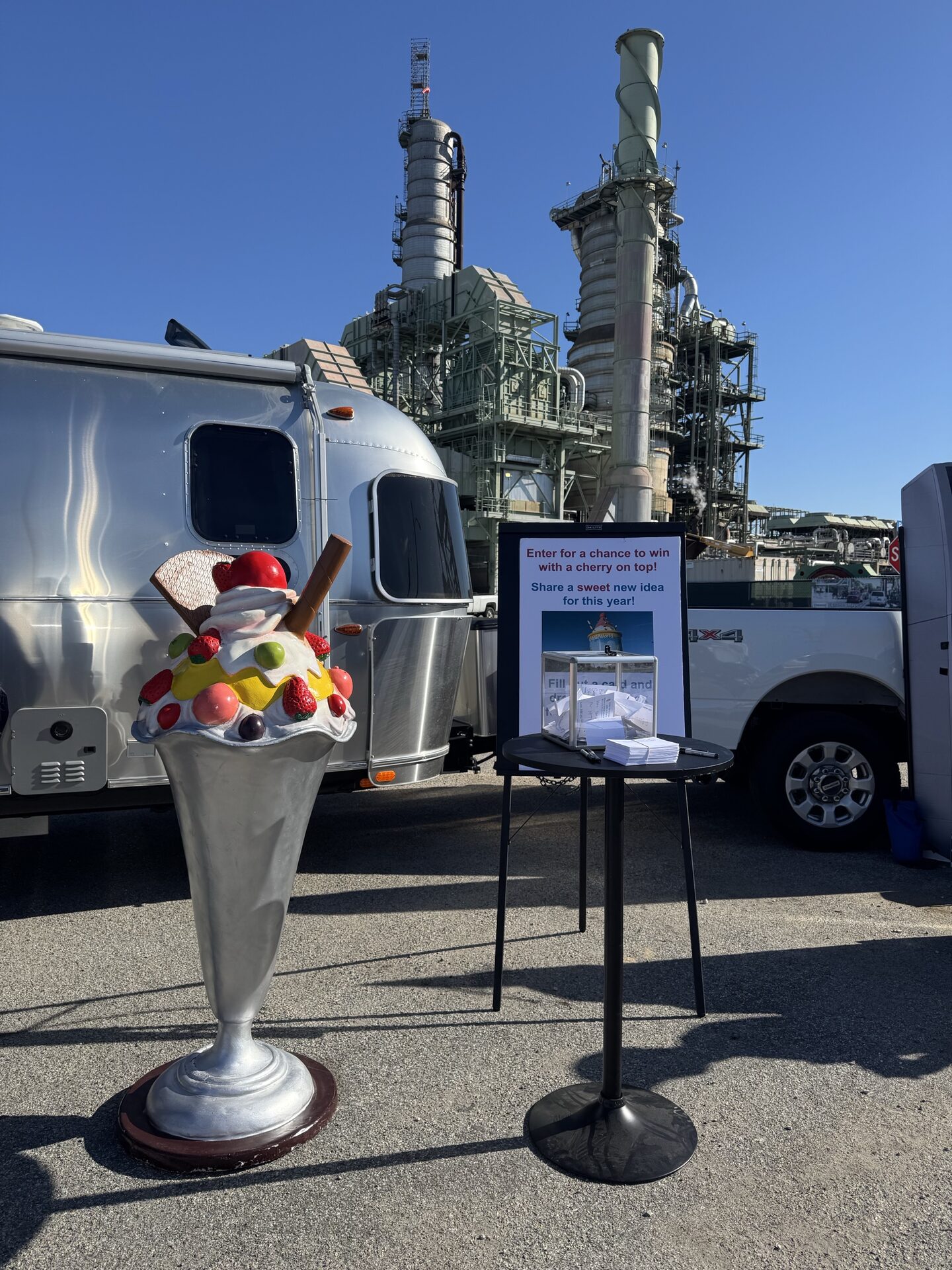 Giant sundae prop and idea raffle table next to an Airstream at the Chevron refinery