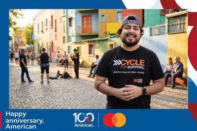 AI travel photo experience for American Airlines' 100th anniversary with Mastercard: a smiling guest in La Boca, Buenos Aires, with street musicians on the cobblestones behind him.