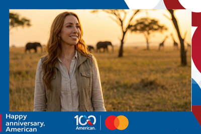 AI travel photo experience for American Airlines' 100th anniversary with Mastercard: a guest on safari at golden hour, elephants and giraffes grazing across the savanna behind her.