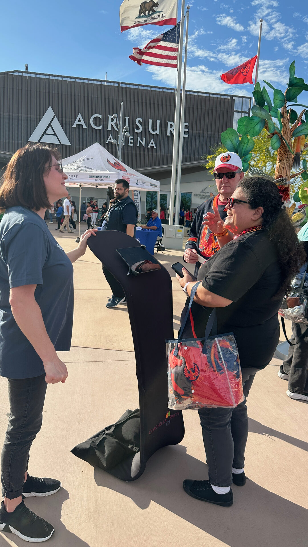 Two guests standing by the photo booth holding a swag bag