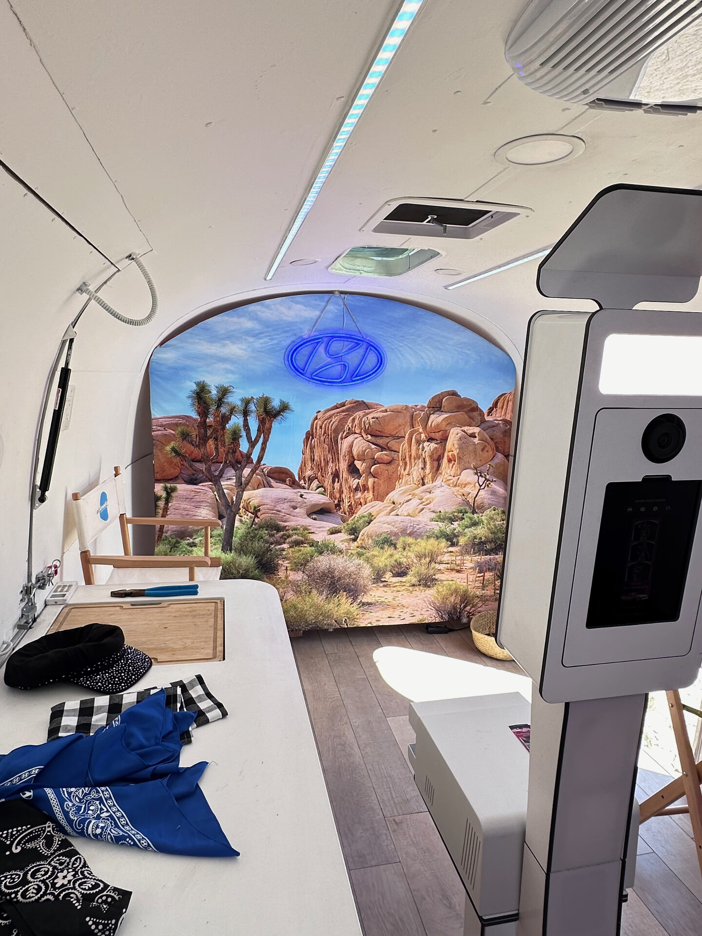 Photo booth kiosk inside an Airstream with a painted Joshua Tree desert mural backdrop