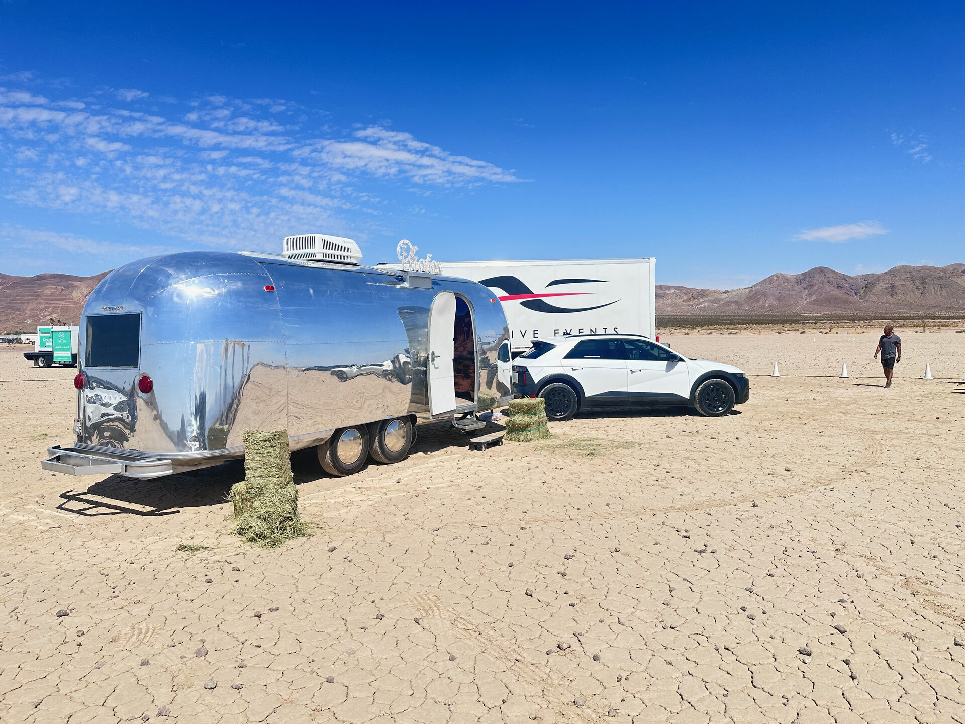 Polished Airstream trailer beside a white Hyundai IONIQ 5 on a cracked desert lake bed