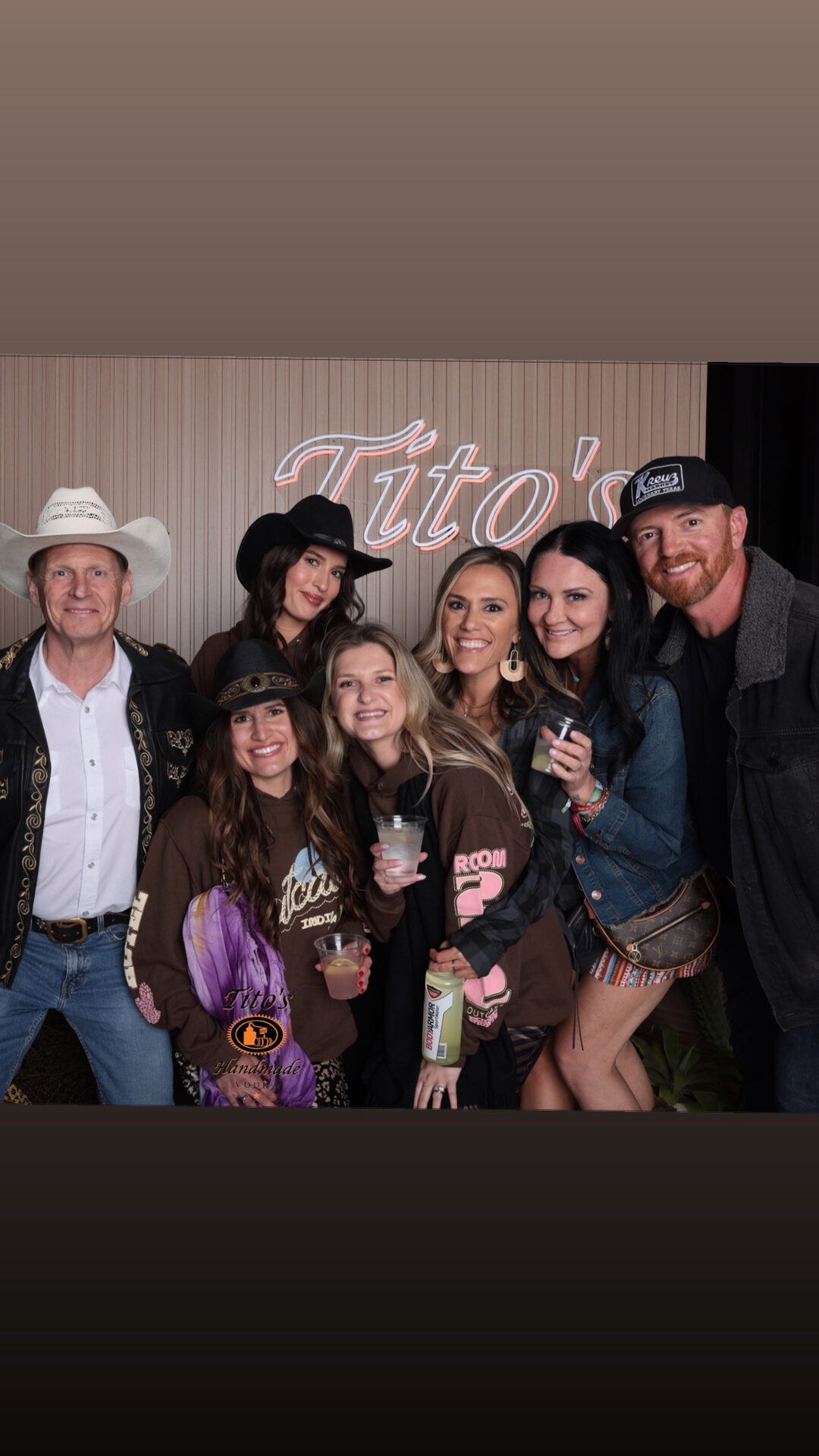 Group of guests in western hats at the Tito’s branded backdrop