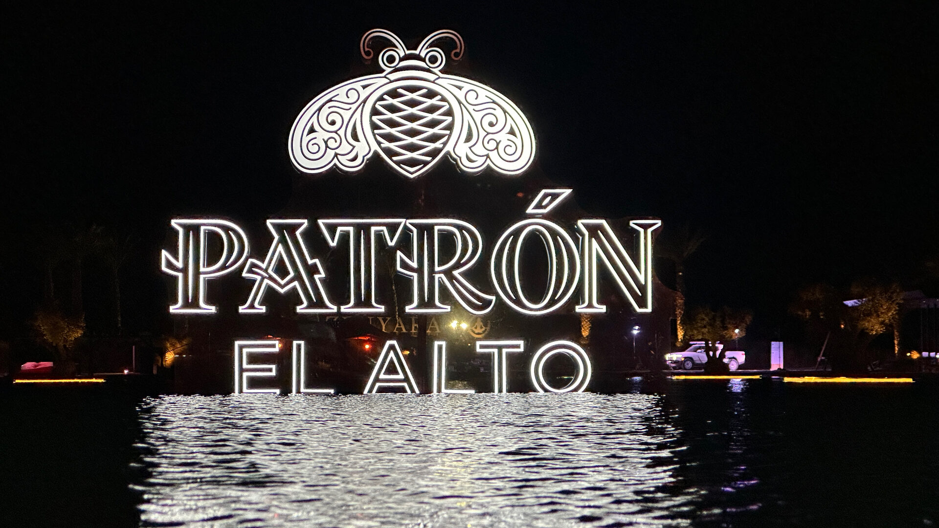 Patron El Alto logo projected onto the surface of a lagoon at night