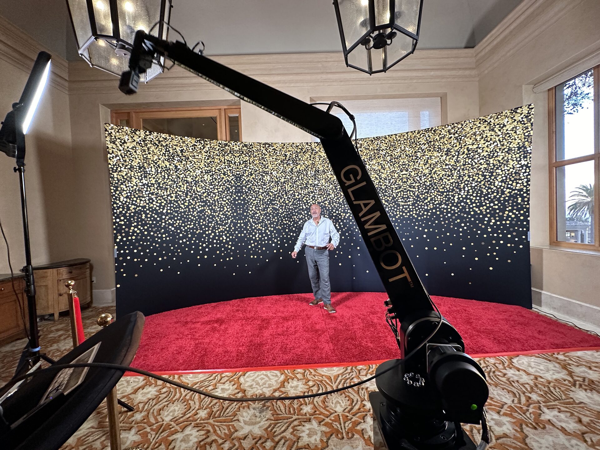 The GlamBot camera arm, red carpet and gold-flecked backdrop set up in a ballroom at The Resort at Pelican Hill, Newport Beach