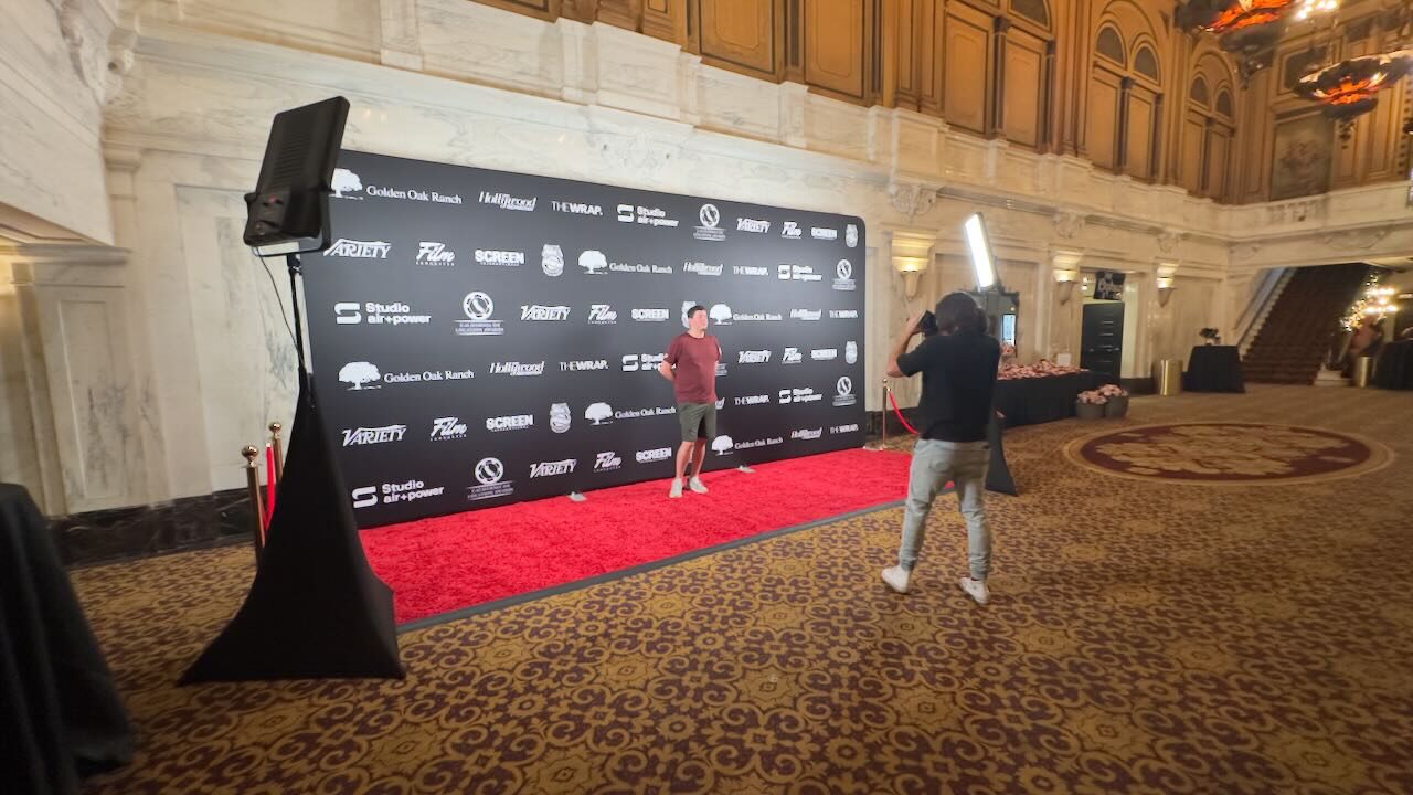 A red carpet arrival area lit for filming at an evening event