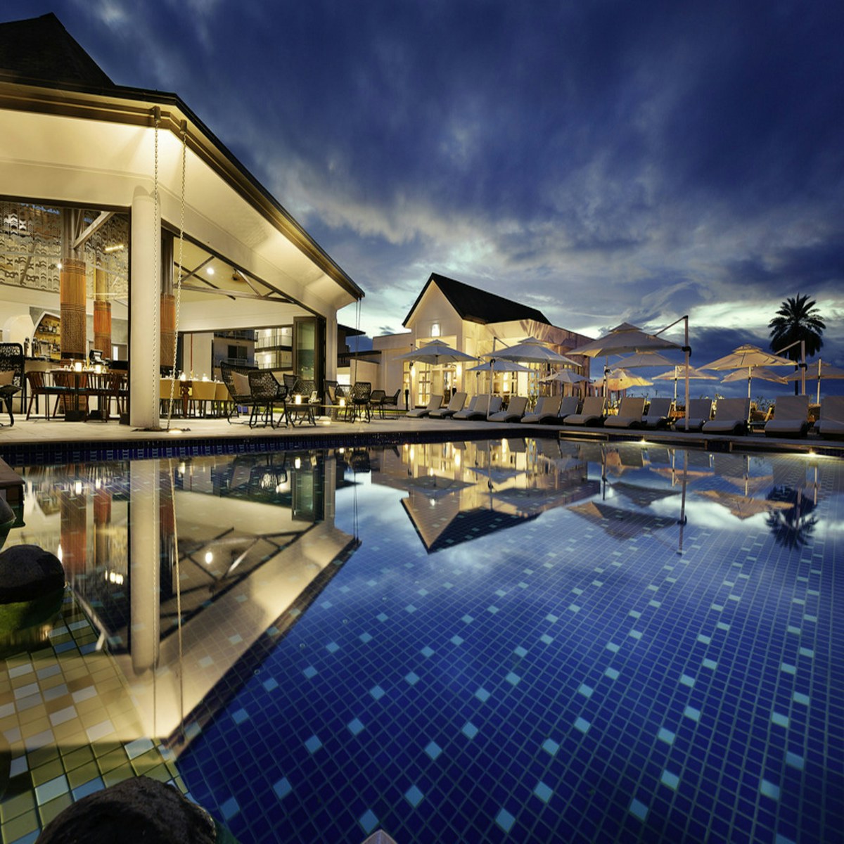 Resort pool with loungers beside a coastal hotel