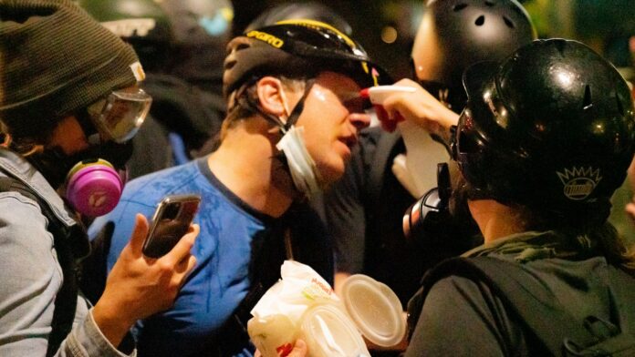 Portland police declare riot as demonstrators attack fence outside federal courthouse